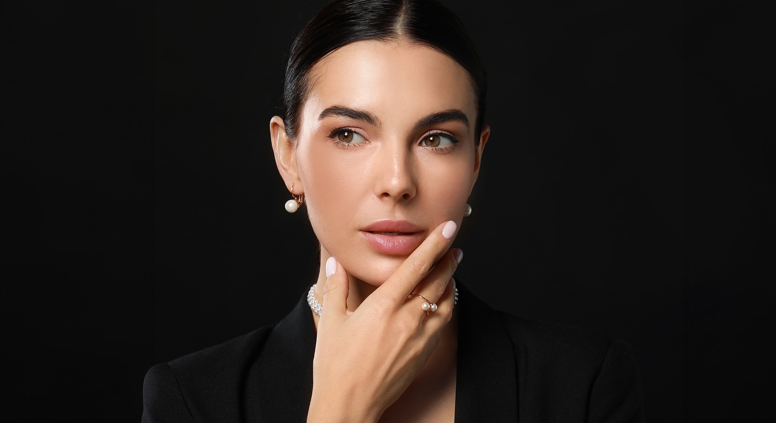 Bakersfield liquid rhinoplasty model with elegant jewelry, thoughtful expression.